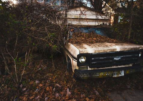 Old junk Chevy truck with modified roof in woods to be taken by junk removal service